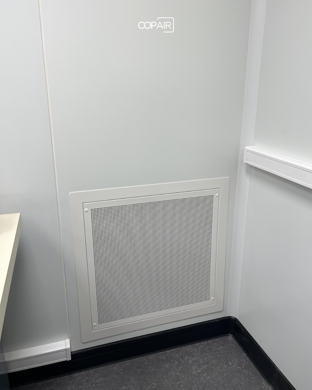 Grille de reprise d'air murale installée dans une salle de métrologie industrielle climatisée, COPAIR