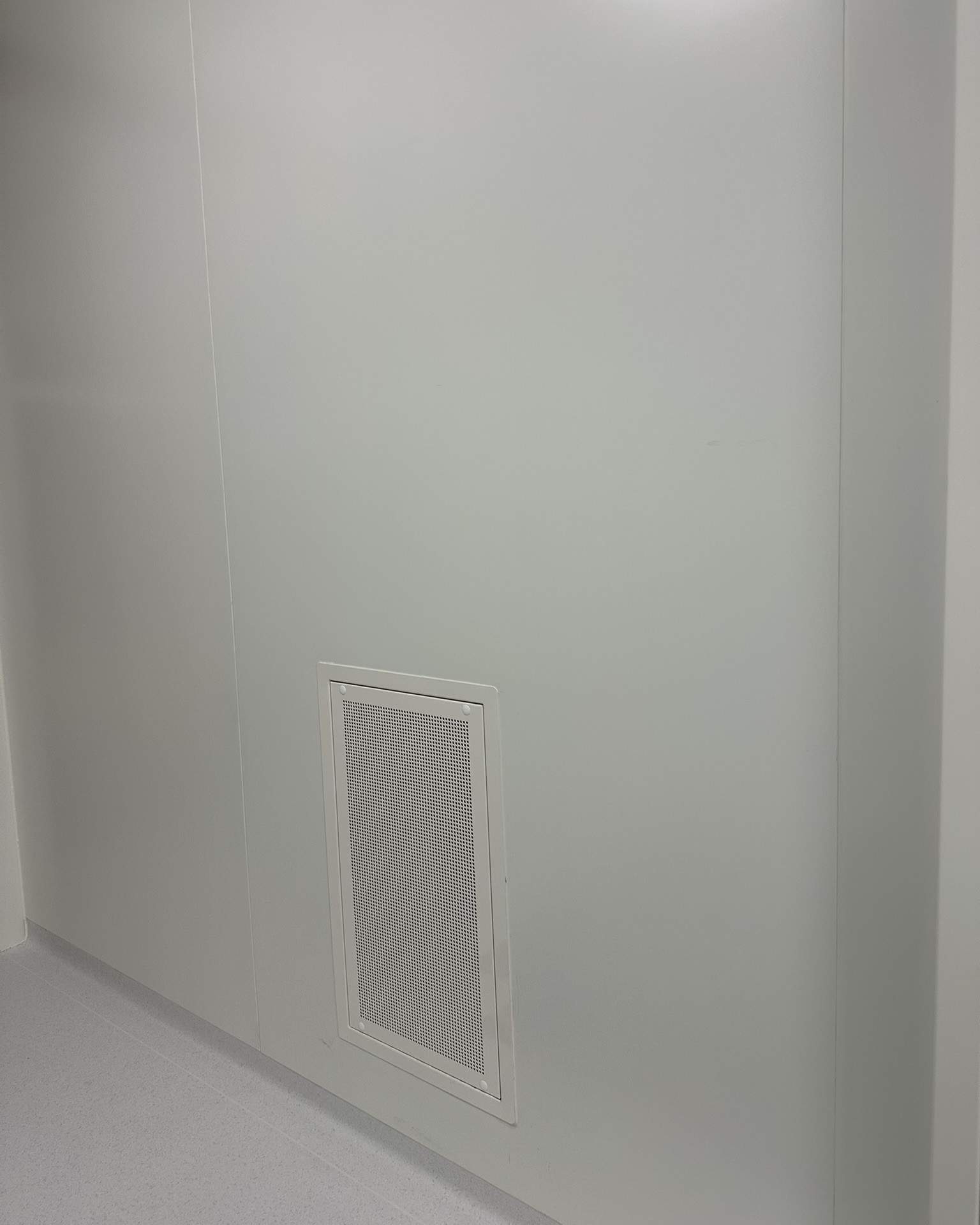 Grille de ventilation murale discrète installée dans une salle propre pharmaceutique