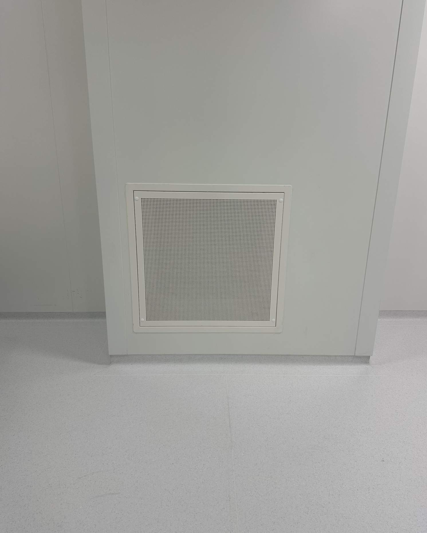 Grille de diffusion d'air perforée installée en bas de mur dans une salle propre